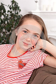 Portrait of a teenager girl with freckles sit on her favorite cozy sofa