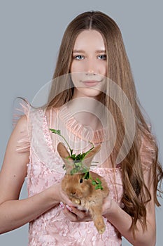 Portrait of a teenager girl with long blond hair and a red rabbit