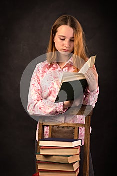 Portrait of a teenager girl reading book. Stack of books.