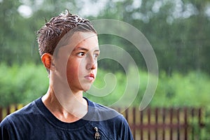 Portrait of teenager. a man stands in the rain and looks into the distance.