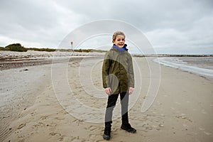 Portrait of teenager staing on coast of Baltic sea with lighthouse on background