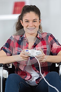 Portrait teenager in wheelchair playing computer game