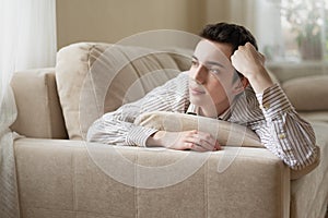 Teenager young man lying on sofa at home