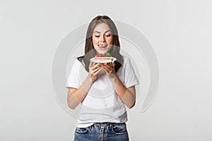 Portrait of tempted beautiful girl licking lips as looking at cake