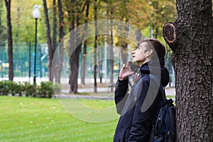 Portrait of Tenager guy with a smartphone talking phone. Park outdoor.