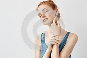 Portrait of tender redhead model posing with closed eyes.