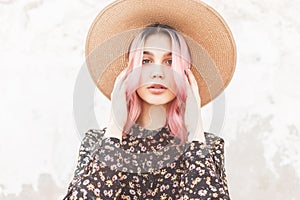 Portrait tender young pretty woman with beautiful pink hair in fashionable straw hat in stylish black dress with floral print on