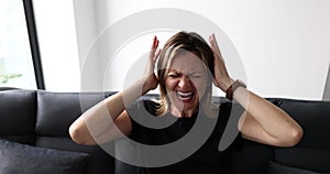 Portrait of tense woman covering her ears with hands and screaming with eyes closed