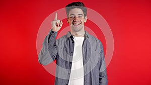 Portrait of thinking pondering man having idea moment pointing finger up on red