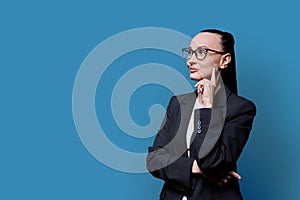 Portrait of thinking serious confident business woman , on blue studio background