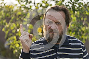 Portrait of a thinking or solve problems senior man. Elderly bearded caucasian male in nature. Face bearded upset male waving his