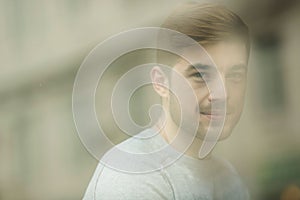 Portrait of thinking young man near glass window. Looking in the window. Reflection from model on the glass.