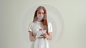 Portrait of thinking young woman scratching head with pencil, writing down idea in notebook, making plans in organize.