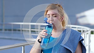 Portrait of thirsty female runner drinking water