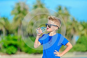 Portrait of a thirsty handsome boy in sunglasses drinking water