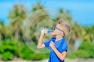 Portrait of a thirsty handsome boy in sunglasses drinking water