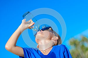 Portrait of a thirsty handsome boy in sunglasses drinking water