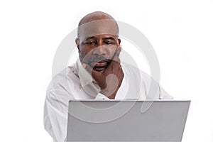 Portrait of thoughful and pensive African American software expert sitting front of a laptop computer.   Contemplating man working