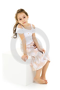 Portrait of Thoughtful Beautiful Girl Sitting on White Cube