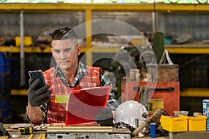 Portrait of Thoughtful Caucasian worker holding a clipboard and used mobile phone while working in industrial factory
