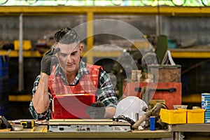 Portrait of Thoughtful Caucasian worker holding pencil and looking at clipboard while working in industrial factory