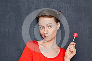 Portrait of thoughtful dreamy young woman holding pink lollipop