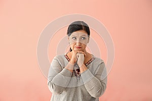 Portrait of thoughtful mature woman on color background