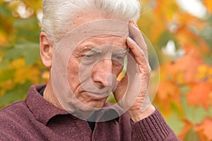 Portrait of thoughtful senior man in autumn park