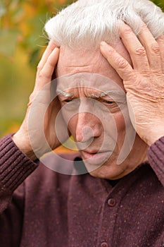 Portrait of thoughtful senior man in autumn park