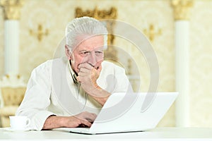 Portrait of thoughtful senior man with laptop