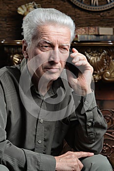 Portrait of thoughtful senior man with smartphone