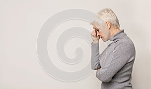 Portrait of thoughtful senior woman on light studio background