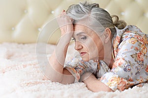 Portrait of thoughtful senior woman lying on bed