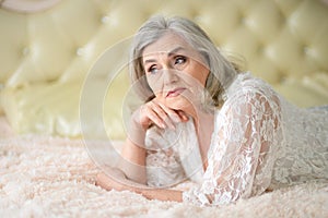 Portrait of thoughtful senior woman lying on bed