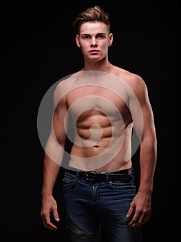 Healthy teenage guy shirtless on a black background. Sporty young men. Muscle building concept.