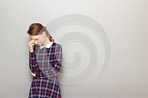 Portrait of thoughtful tired girl touching bridge of nose with hand