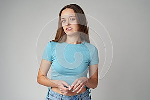 Portrait of thoughtful uncertain young casual girl on gray background