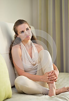 Portrait of thoughtful woman sitting on divan