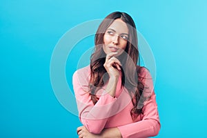 Portrait of thoughtful wondering woman looking sideways isolated over blue background photo