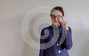 Portrait of a thoughtful young asian Chinese woman in eyeglasses looking up at copy space with hand on her head isolated over