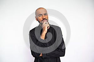 Portrait of thoughtful young man standing with hand on chin