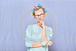 Portrait of thoughtful young woman with colorful hair curlers on head