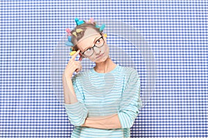 Portrait of thoughtful young woman with colorful hair curlers on head