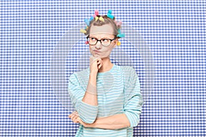 Portrait of thoughtful young woman with colorful hair curlers on head