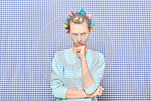 Portrait of thoughtful young woman with colorful hair curlers on head