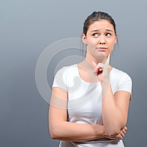 Portrait of thoughtful young woman looking above against gray background