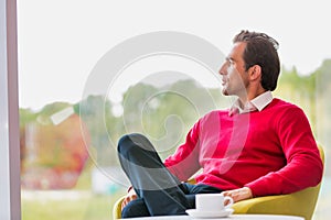 Portrait of thougtful businessman sitting while drinking coffee in lobby