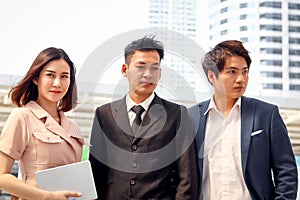 Portrait of three Asian businessman and businesswoman confidential standing in the city, businesspeople talking about job while