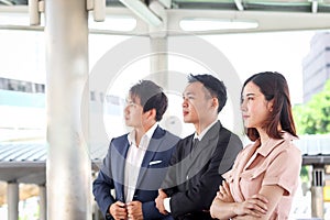 Portrait of three Asian businessman and businesswoman confidential standing in line and looking the same way, businesspeople