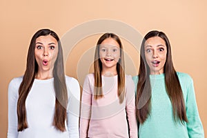 Portrait of three attractive cheerful amazed girls news reaction isolated over beige pastel color background